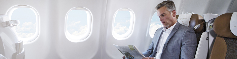 Homem sentado no avião, lendo um jornal